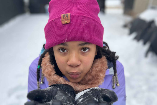 Petite fillant jouant sous la neige avec le bonnet hiver en satin