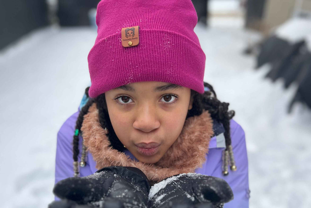 Petite fillant jouant sous la neige avec le bonnet hiver en satin