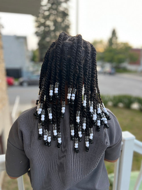 Petite fille de 10 ans avec une coiffure protectrice et des perles noires et blanches au bout de ces twist