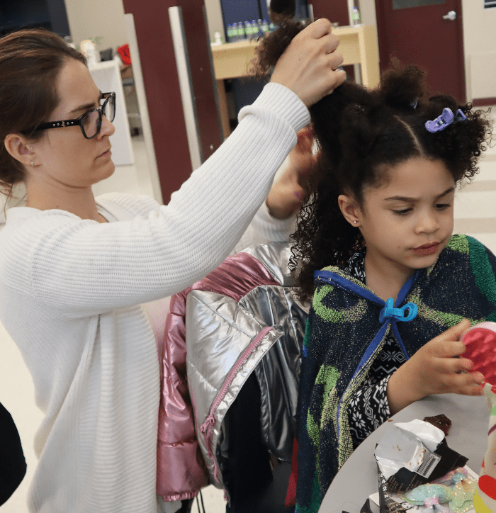 Maman caucasienne au cheveux lisse qui apprend a coiffer sa fille mtisse aux cheveux texturés