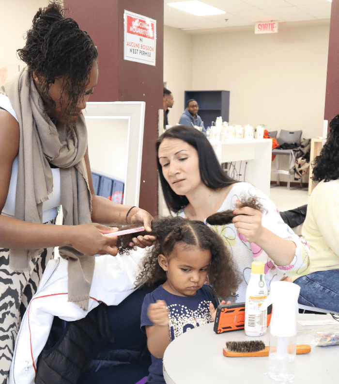 Schamme rosidor qui aide une maman a coiffer sa fille aux cheveux bouclés