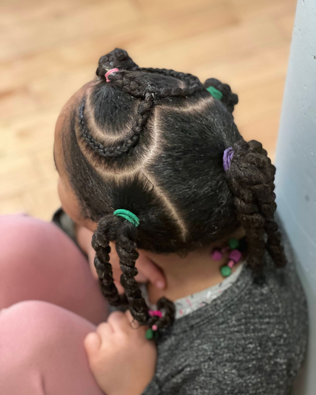 Vue du dessus montrant les tracés nets et les twists avec élastiques colorés sur cheveux texturés.