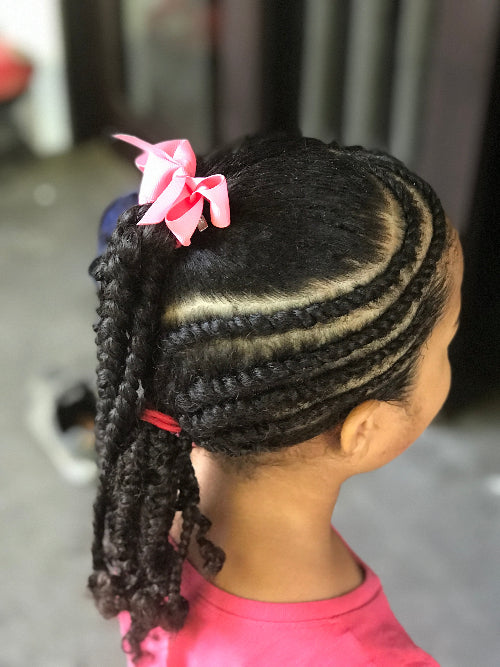 Vue de profil d’une coiffure avec tresses collées vers l’arrière et nœud rose, idéale pour cheveux afro ou frisés.