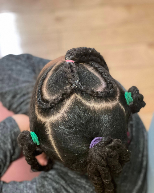 Vue aérienne d’une coiffure twist en forme de cœur avec des tracés très nets et élastiques colorés.